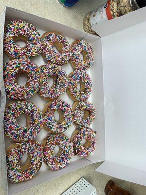 Twelve perfect chocolate iced with sprinkles.