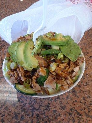 Bowl of chicken with avocados on top.