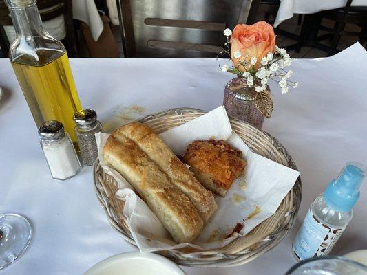 Basket of delicious cheesy bread and pizza bread, with a fresh rose at every table.