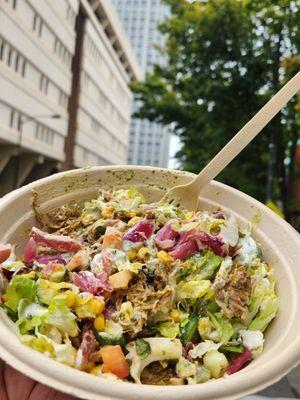 Salad bowl with fresh toppings like corn, pickled red onions, Persian cucumbers,  tomatoes, braised lamb