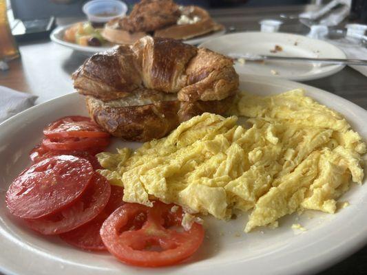 2 Eggs with sliced tomatoes and a croissant