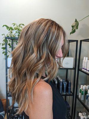 Natural lived-in highlights, wavy hair.