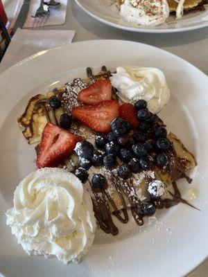 Sweet ricotta filled crepes with berries and Nutella drizzle.