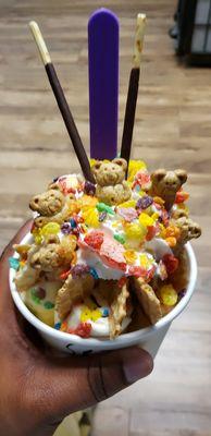 Birthday cake base with sprinkles. Topped with fruity pebbles, waffle cone pieces, teddy grahams, and pocky.