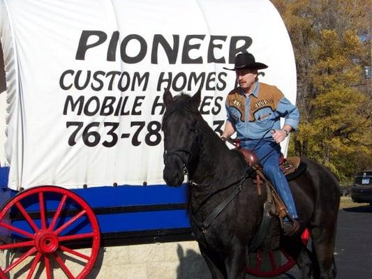 Jeff Comiskey Pres. playing cowboy and Pioneer Mobile Homes Inc. and Pioneer Custom Homes Inc. parking lot.