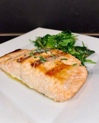 Grilled salmon entrée served with sautéed spinach