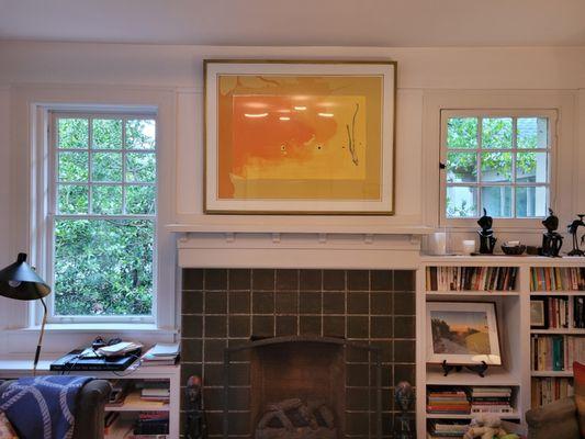 Large Framed Artwork mounted on plaster wall above fireplace mantel.