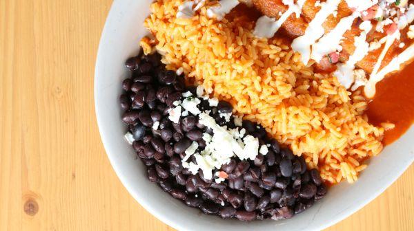 A peak at our flavorful enchiladas served with a side of Mexican rice and black beans