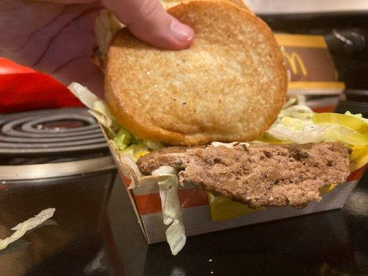 Box where burger patty hanging out of box, lid closed over it.