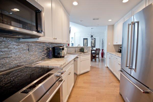 Galley kitchen with white cabinet and glass mosaic backsplash. design and installed by Tile Center