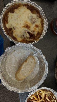 Chicken parmigiana with fettuccine noodles. Empty Caesar salad in the middle with a piece of the bread they include with your entree