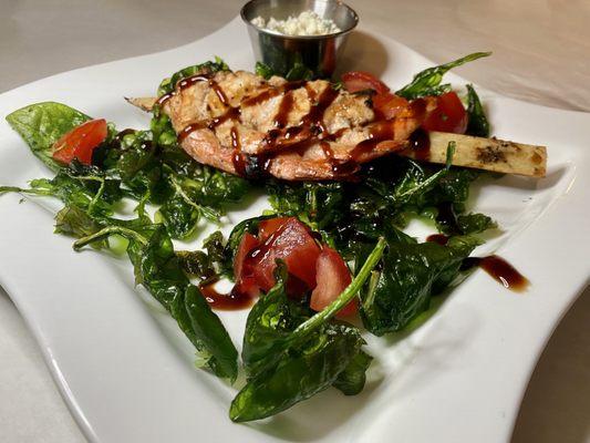 Shrimp with sugar cane and balsamic vinegar garnished with fried spinach and tomatoes.