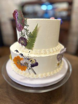 Vanilla on vanilla wedding cake decorated with dried pressed edible flowers