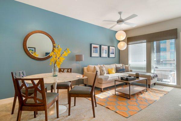 Carpeted and staged living room and dining area with large windows.