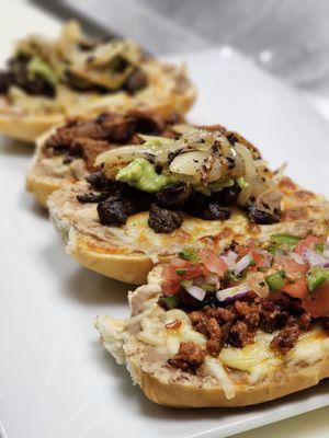 Molletes topped with chorizo, asada, carnitas