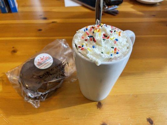 Hot chocolate with marshmallows, whipped cream and sprinkles, and a gluten free vegan double chocolate cookie sandwich