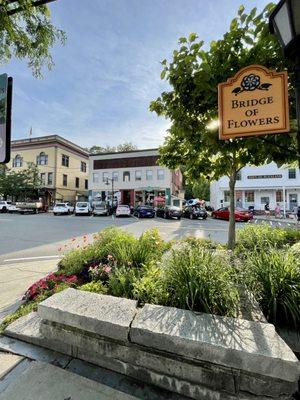 The Bridge of Flowers Sign with Free Parking & the town's stores in the background in Shelburne Falls MA