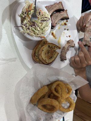 Ribs, coleslaw, onion rings, and garlic bread.