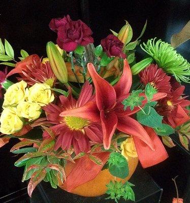 Beautiful fall flowers in a fresh carved pumpkin create the perfect table arrangement.