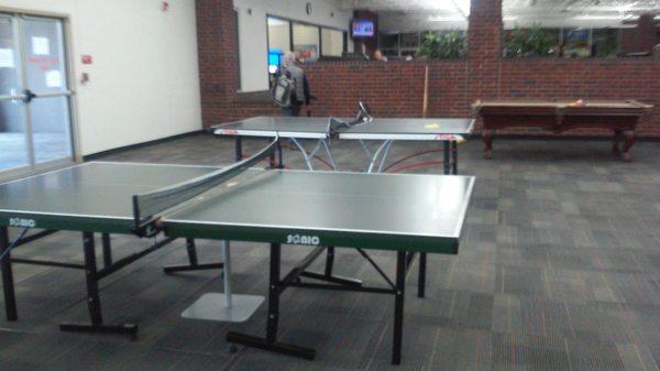 Twin ping pong tables with screwed up nets, broken down pool table in background