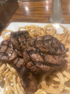 Marinated steak tidbits over onion straws