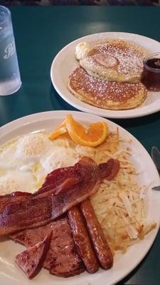 Combination breakfast.  Ham, bacon and sausage with three eggs, hash Browns and pancakes.