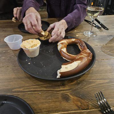 Half of the soft pretzel with mustard and another spread with caraway seeds