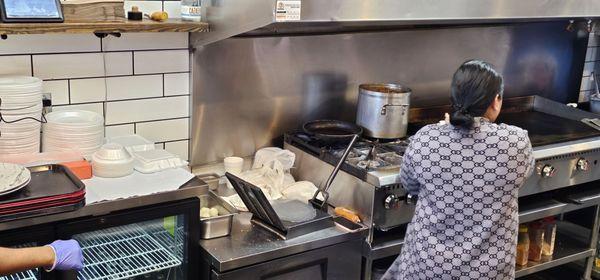 She takes the fresh dough, presses them 8nto tortillas, then puts them on the griddle