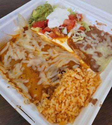 Beef enchiladas with rice beans and shredded lettuce guac, and tomatoes