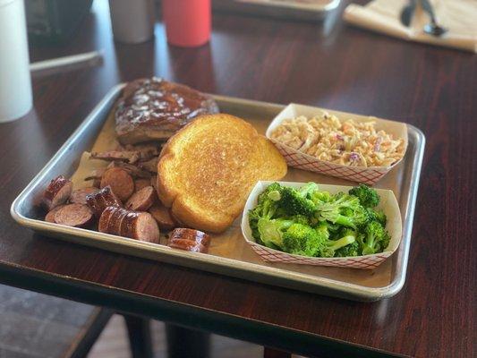 Three Meat Plate with beef brisket, sausage, pork spareribs, cajun slaw, steamed broccoli, and garlic toast