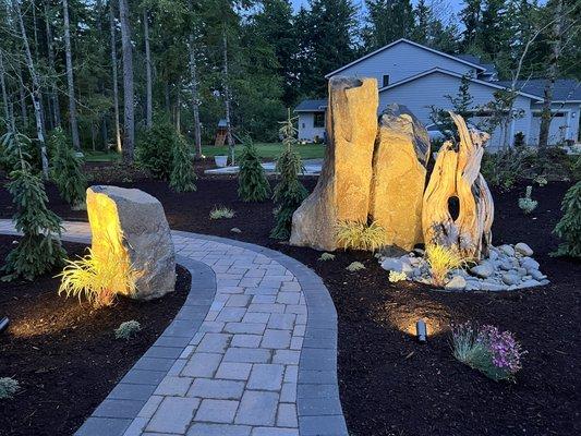 Paver walkway/entryway into the backyard with vertical column rocks and driftwood