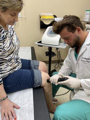 Dr. Bourgeois performing acoustic compression therapy on a patient's right knee.