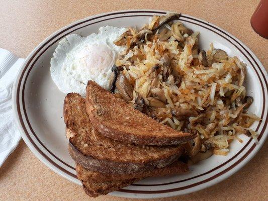 One egg over easy, hash browns with mushrooms, wheat toast, and a large tomato juice.