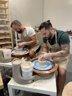 My husband and I making bowls on pottery wheels in Mercy Pottery's studio