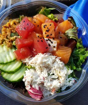 Poke bowl with salmon, tuna, cucumbers, crab salad, green salad, seaweed salad, crispy onions