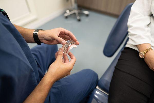 Dr. Anthony M. Pikos shows a patient how Same Day Teeth® dental implants will look when completed.