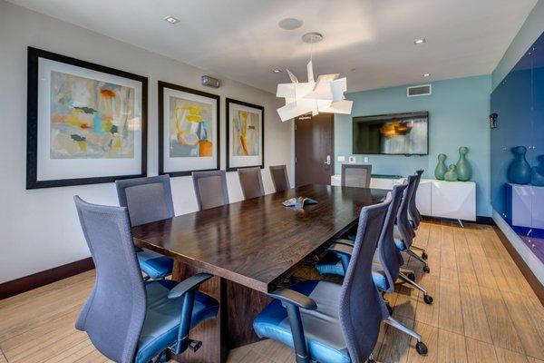 Conference room with large TV, a table, and chairs.