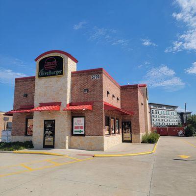 Olive Burger with drivethru lane, along eastbound frontage road of 121 Sam Rayburn Frwy, west of Parkwood Blvd.