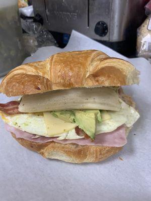 Croissant breakfast sandwich with ham eggs avocado bacon and cheese and a chicken tamale