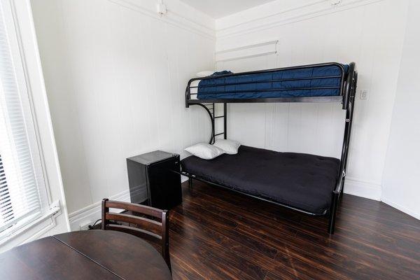 Full sized bed and refrigerator in single room.