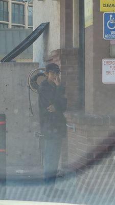 Employee smoking near the gas pump.