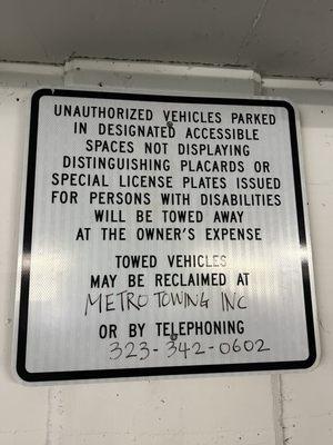 A clear sign posted by the building, indicating the parking policy for handicap spots for which they do not abide by