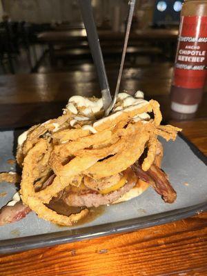 THE MILLIONAIRE Open-faced burger w/ wagyu, cheddar, truffle aioli, garlic mushrooms, bacon, dark beer sauce, crispy fried onion strings.