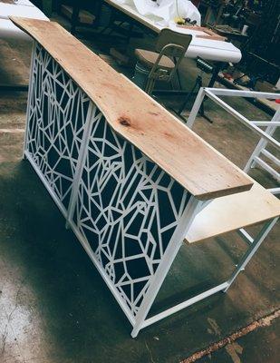 Custom reception desk with laser cut steel front and live-edge pecan top.