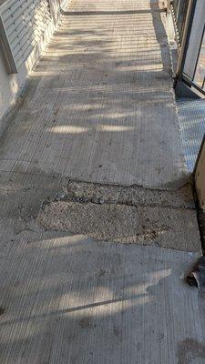 Spalling concrete on the walkway of the second story (cracking and breaking away).