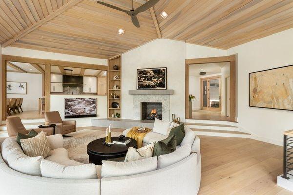 Great Room with curved sectional, white oak timbers and floors, and a plaster and concrete fireplace surround