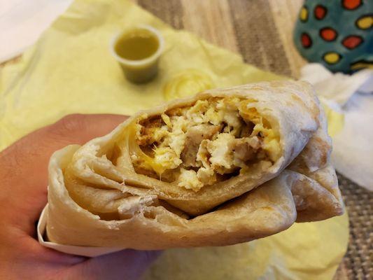 One bite into sausage breakfast burrito without potatoes.