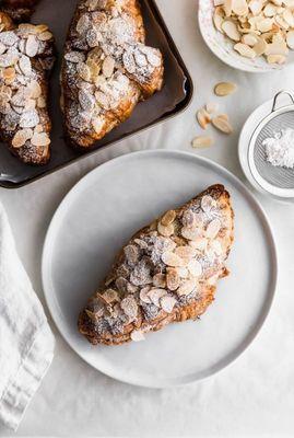 Almond croissants, freshly baked with a buttery pastry, filled with almond cream, and topped with toasted almonds.