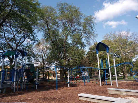 Children's playground appointed with jungle area and swings. Trees offer lots of shade on hot days