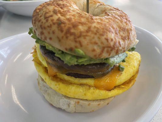 Egg, smashed avocado, impossible sausage cheddar cheese on an Asiago bagel